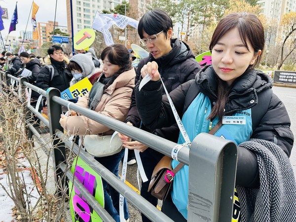 경기도교육청 인근 담장에 ‘경기도교육감에게 바란다’ 띠지를 묶는 이재민 지부장.